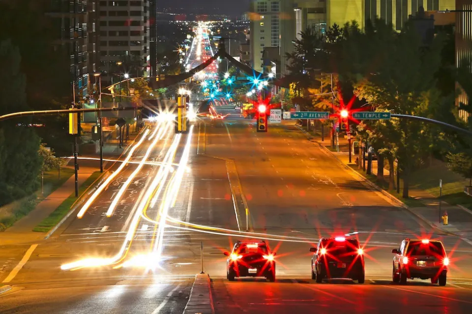 Three cars stopped at a traffic light in downtown Salt Lake City, Utah at night.